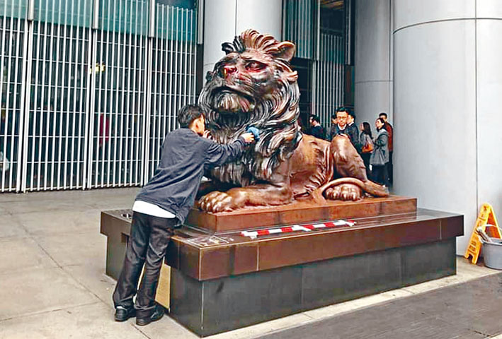 中環滙豐銀行獅子銅像遭噴漆及縱火，職員早上進行清理。港台畫面