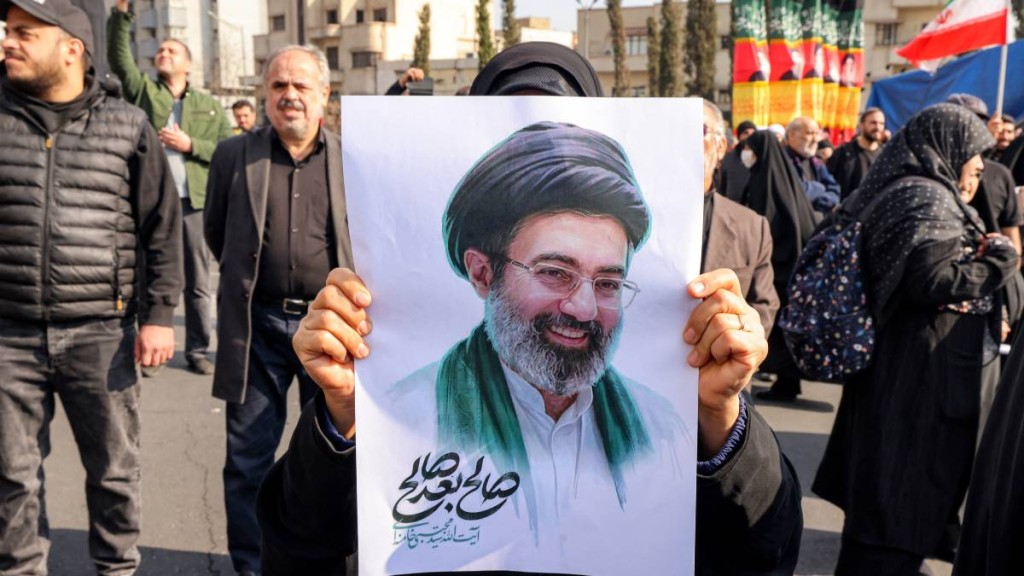 一名女子昨日持伊朗新的最高領袖穆傑塔巴的照片參加集會。（法新社）
