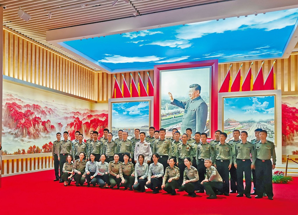 军人参观国防建设成就展，在习近平画像前合影。