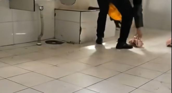黑衣男子將幾塊在地上的冷凍豬肉，放進公廁水池中沖洗。新浪財經