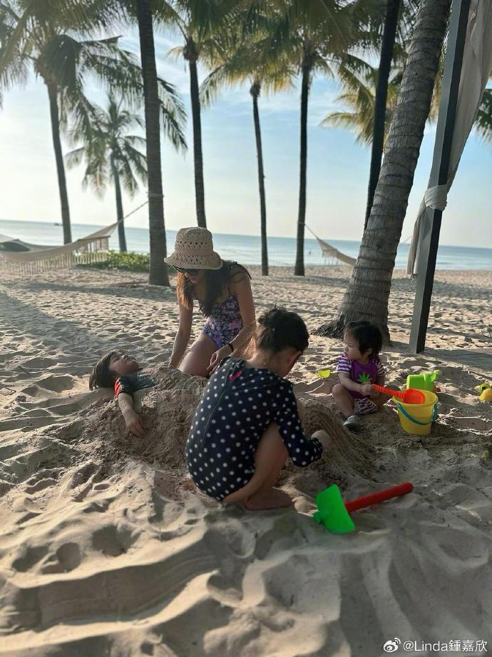 鍾嘉欣在沙灘上與子女一起玩堆沙。