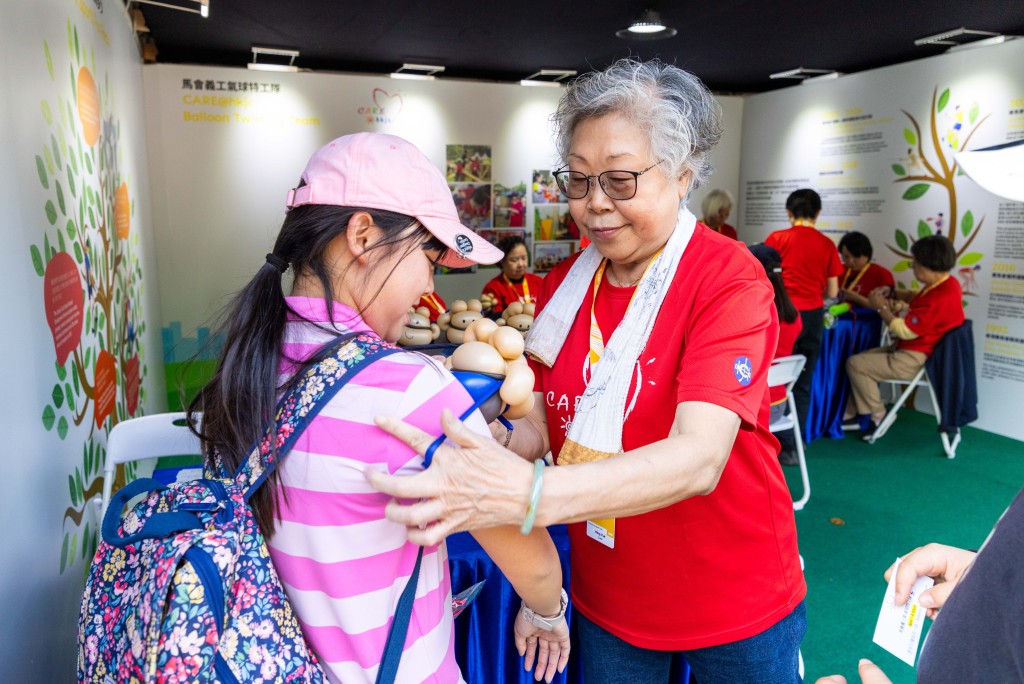 马会义工队 CARE@hkjc 成员在观众村制作气球公仔，为入场观众增添欢乐。