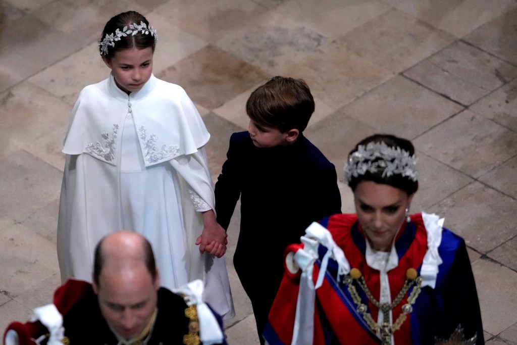 夏洛特公主牽着弟弟路易王子的手，跟隨父母進入西敏寺就坐。 路透社