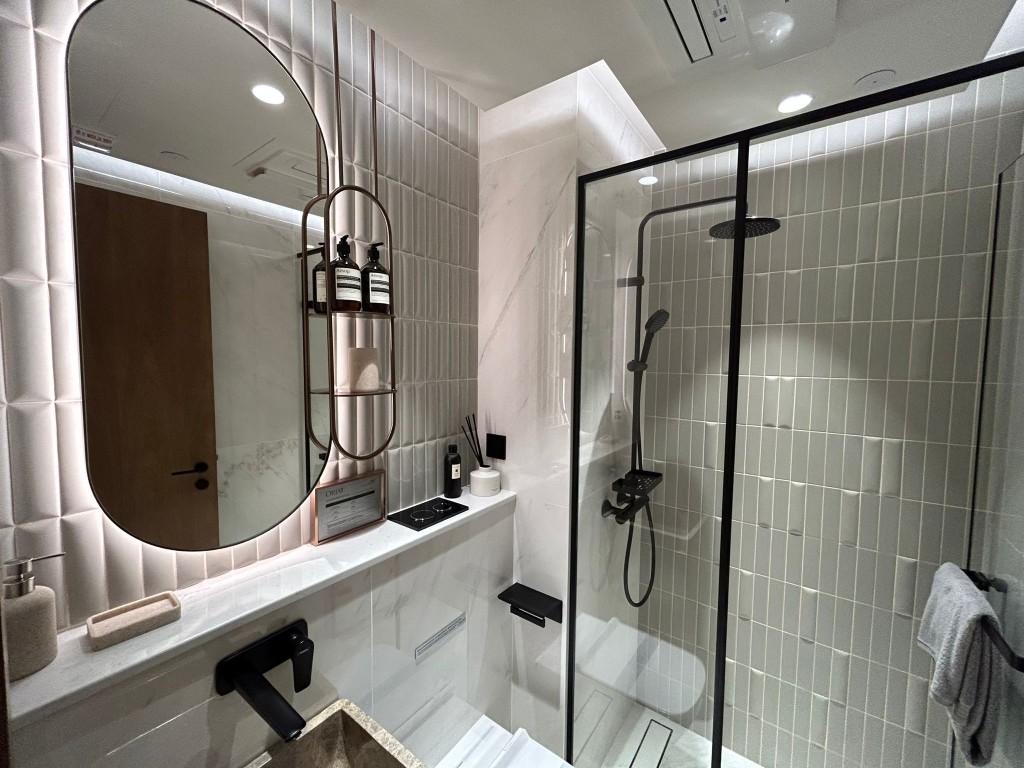 半開放浴室以灰白色作主調，地板以米白及大理石紋瓷磚做分隔，整體盡顯簡約生活的設計態度。