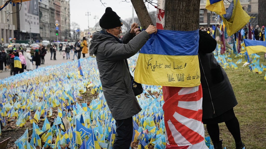  一名75岁日籍义工在基辅市中心阵亡者纪念碑前挂起乌克兰国旗。 美联社