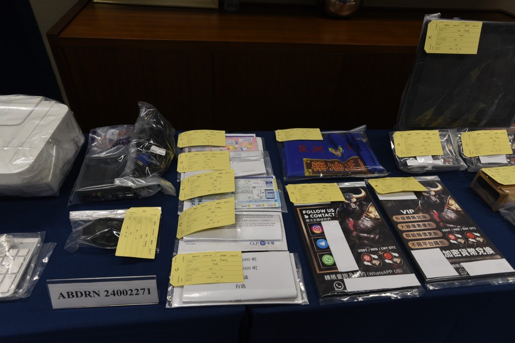 警方檢獲一批證物，包括銀行咭、電腦、點鈔機、兌換加密貨幣的收據、易拉架、海報及卡片等。