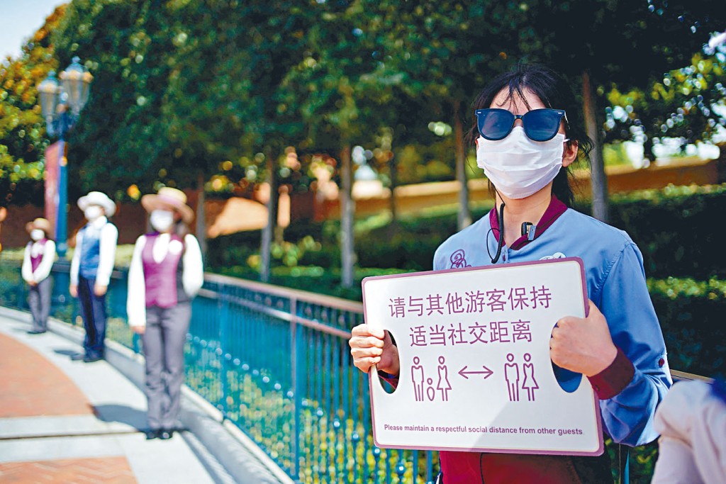 上海迪士尼等企業,拒絕招聘新冠康復者。圖為上海迪士尼職員,呼籲遊客保持社交距離。