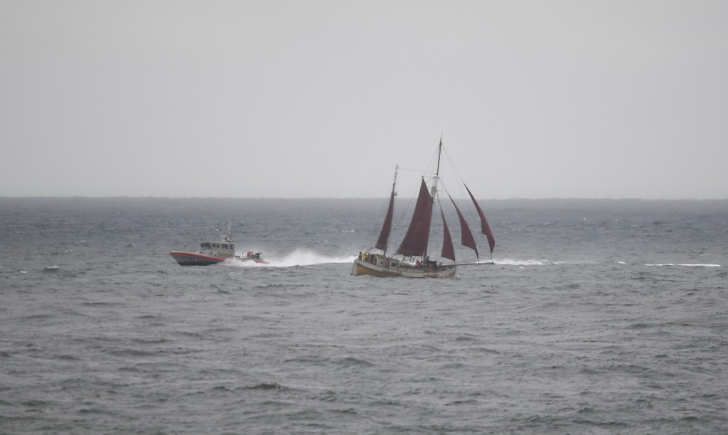 一艘美國海岸警衛隊的小船正進行搜尋工作從經過的帆船附近駛過。AP圖片