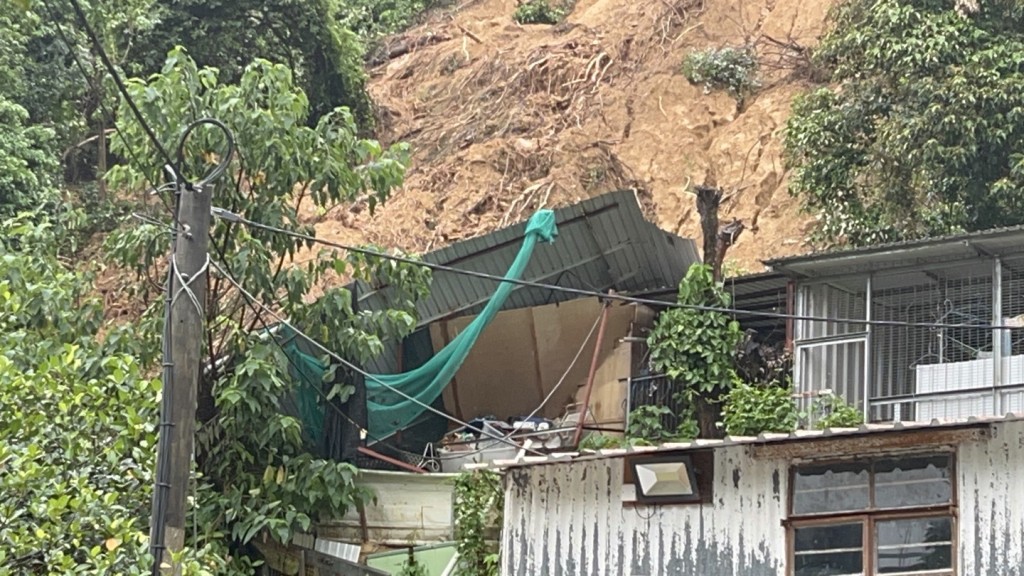 山坡旁一間鐵皮屋被山泥壓毀。