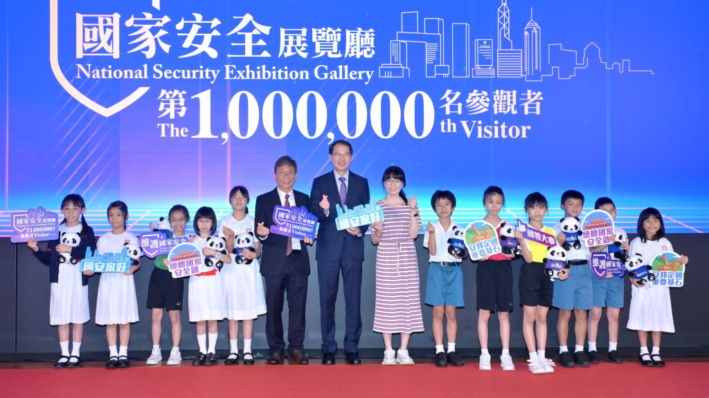 區志光（左七）與國家安全展覽廳第100萬名參觀者合照。政府新聞處