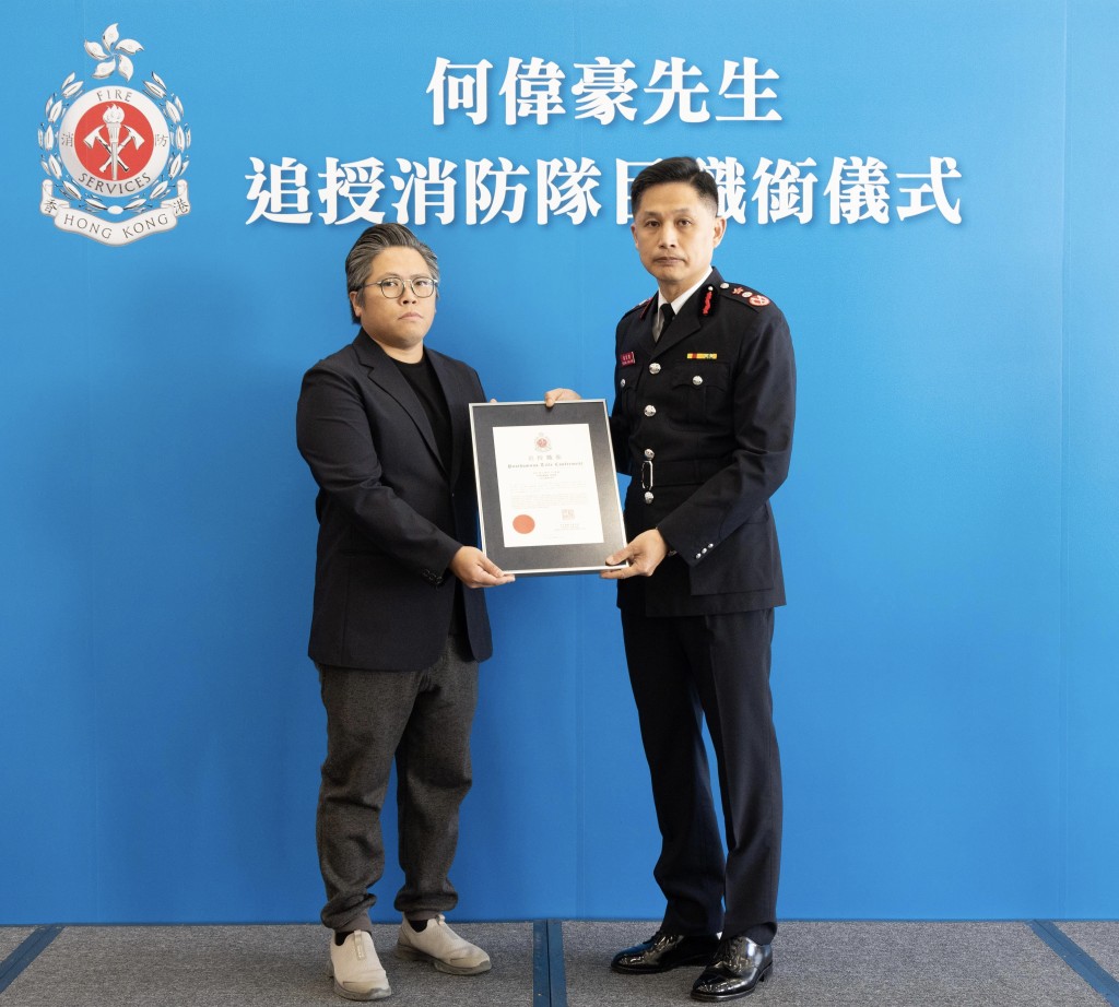 消防處處長楊恩健（右）頒授追授函件，由何偉豪家人代表接受。