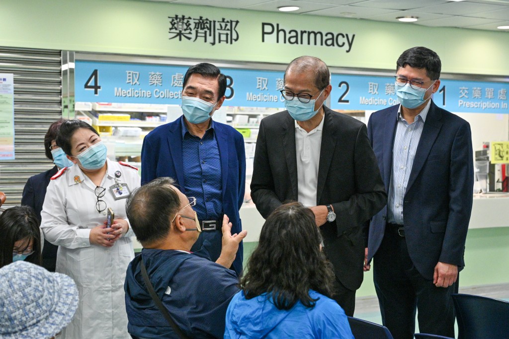 盧寵茂（右二）、范鴻齡（左二）和高拔陞（右一）在西灣河普通科門診診所接種季節性流感疫苗前與市民交流。政府新聞處圖片