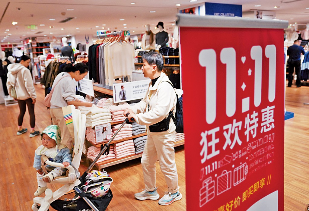 杭州市一間商店內，顧客從「雙11」促銷標識邊走過。