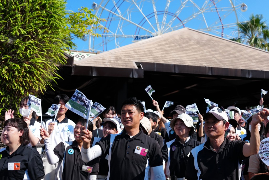 工作人員與當地民眾在日本和歌山縣冒險世界遊樂園外目送運輸大熊貓的運輸車離開。 新華社