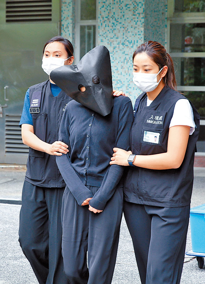 入境處人員將被捕女子蒙頭押走。