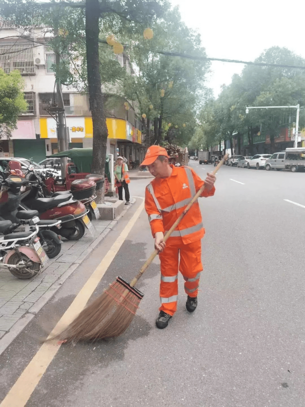 身著橙色工作服，手持掃帚的張相遠。