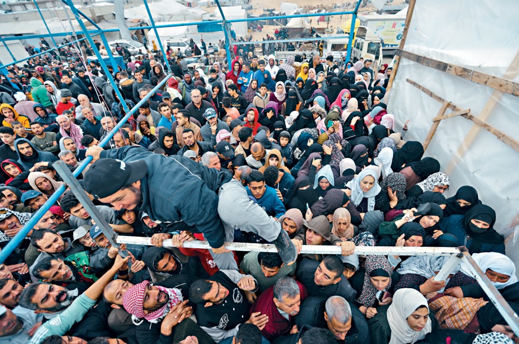 以哈停火期間，加沙南部汗尤尼斯大批巴人聚集，等候領取聯合國機構派發的麵粉袋。