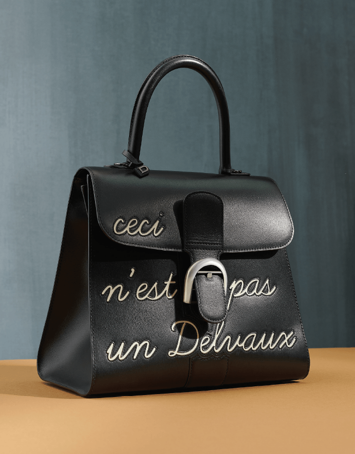 這款經典黑白配「C e c i n' e s t p a s u n Delvaux」手袋是品牌的招牌作之一，亦是向比利時藝術家Rene Magritte致敬之作。