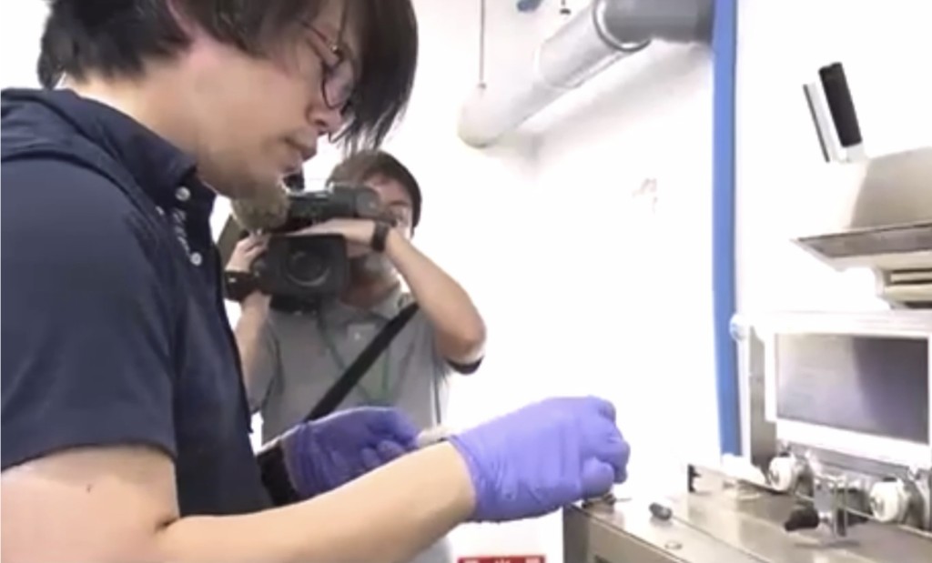 負責人將魚肉放入檢測儀器。 NHK截圖