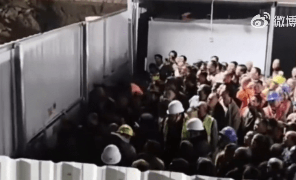 地盤現場聚集大量工人，有人搖晃圍欄高喊「我們要出去吃飯」。