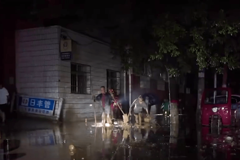 陝西暴雨，民眾及應急人員在街上清除淤泥。