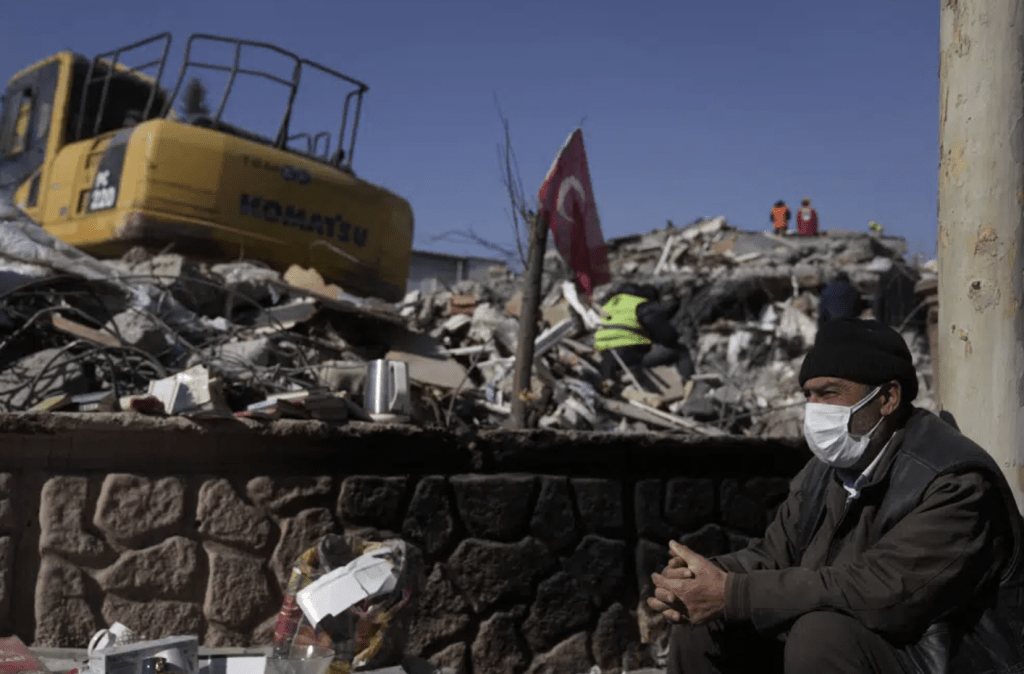 土耳其南部阿德亞曼，一名男子坐在被毀建築物的廢墟旁。AP