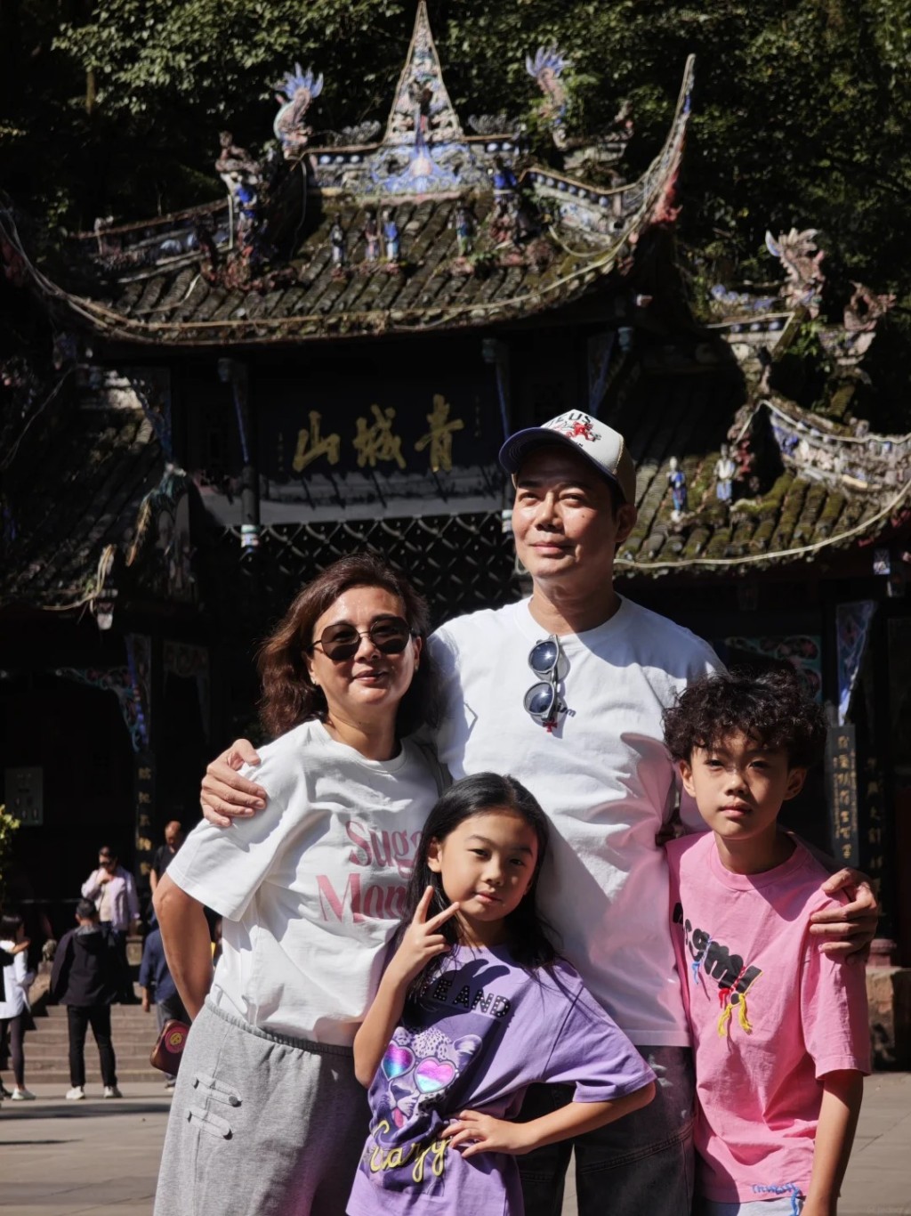 謝天華一家於山門前大合照，8 歲女兒 Mia 對鏡頭舉 V 字手勢非常可愛。