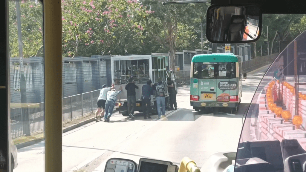 乘客及货车司机等共6人同心协力推开货车。网上片段