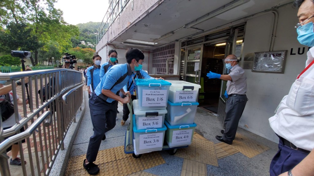 衞生防護中心人員將標示著「撤離用」的箱，帶入大廈。
