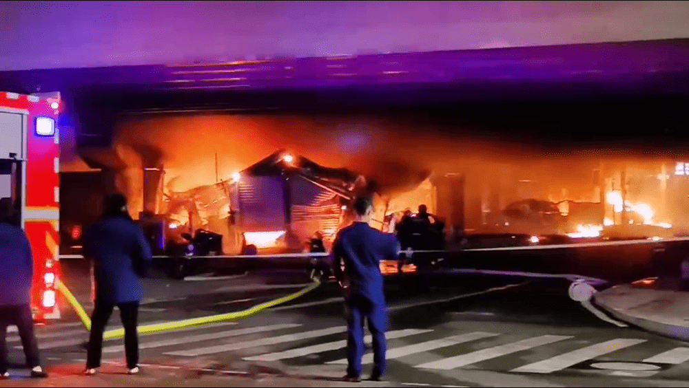 当地消防正扑灭桥下起火的建筑物。