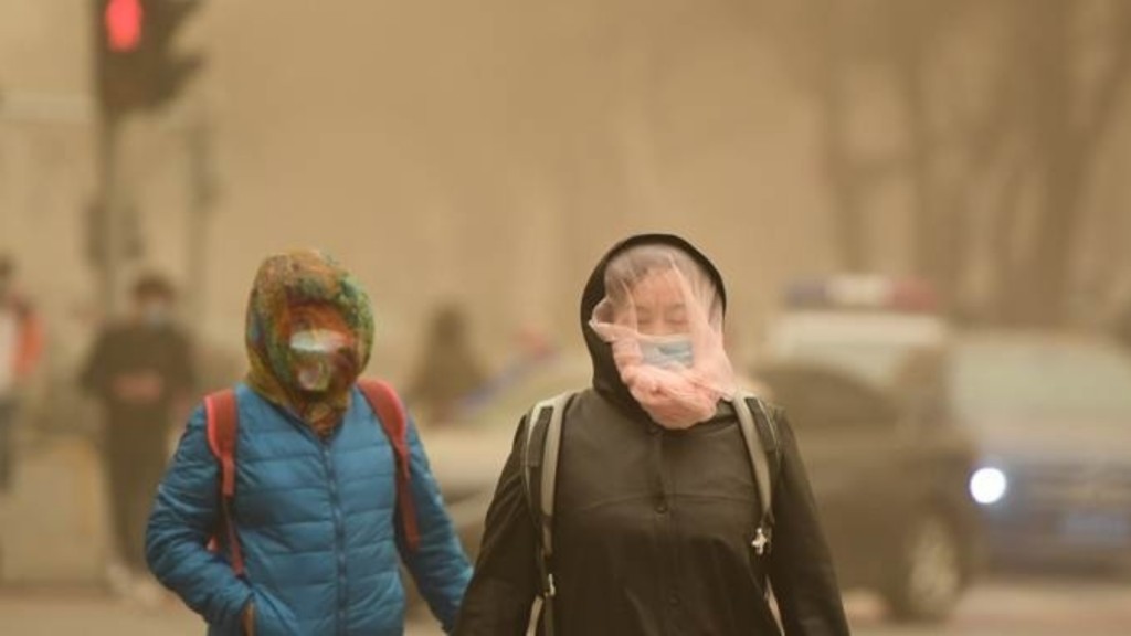 北京市在沙塵天氣下行人都蒙著紗巾出行。新華社