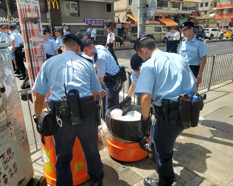 藍帽子警員將路邊的垃圾仔細檢查。梁國峰攝