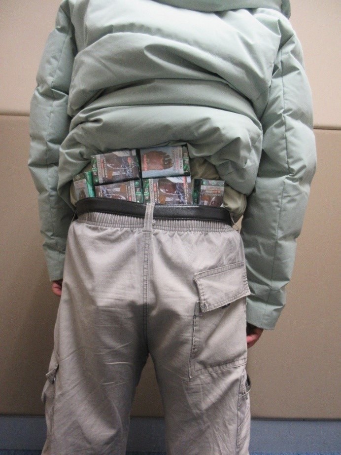 男子在腰間及襪內收藏未完稅香煙。海關圖片