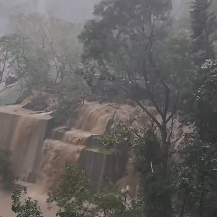 翠林邨彩林楼后山山坡，被大雨不断冲击，沙泥夹杂雨水向下流，形成一道瀑布。网片截图