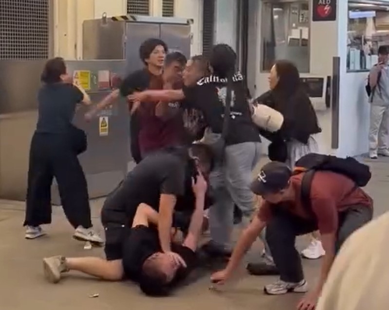 牛仔褲男嘗試揮拳還擊，惟無力掙脫繼續捱打。