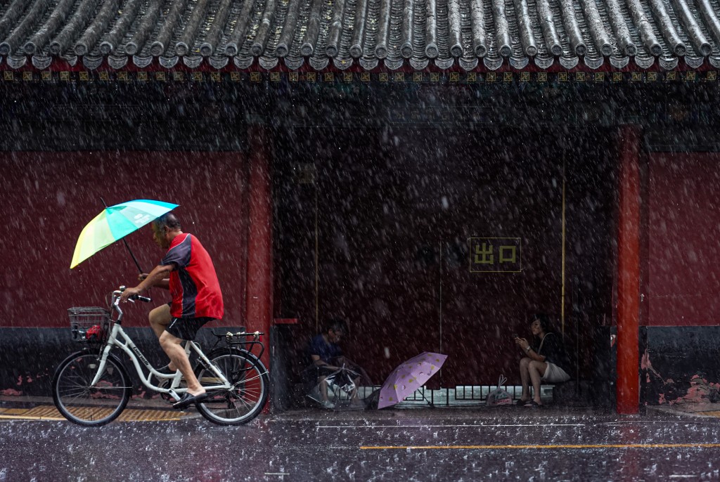 在北京雍和宫大街市民冒雨骑单车前行。新华社