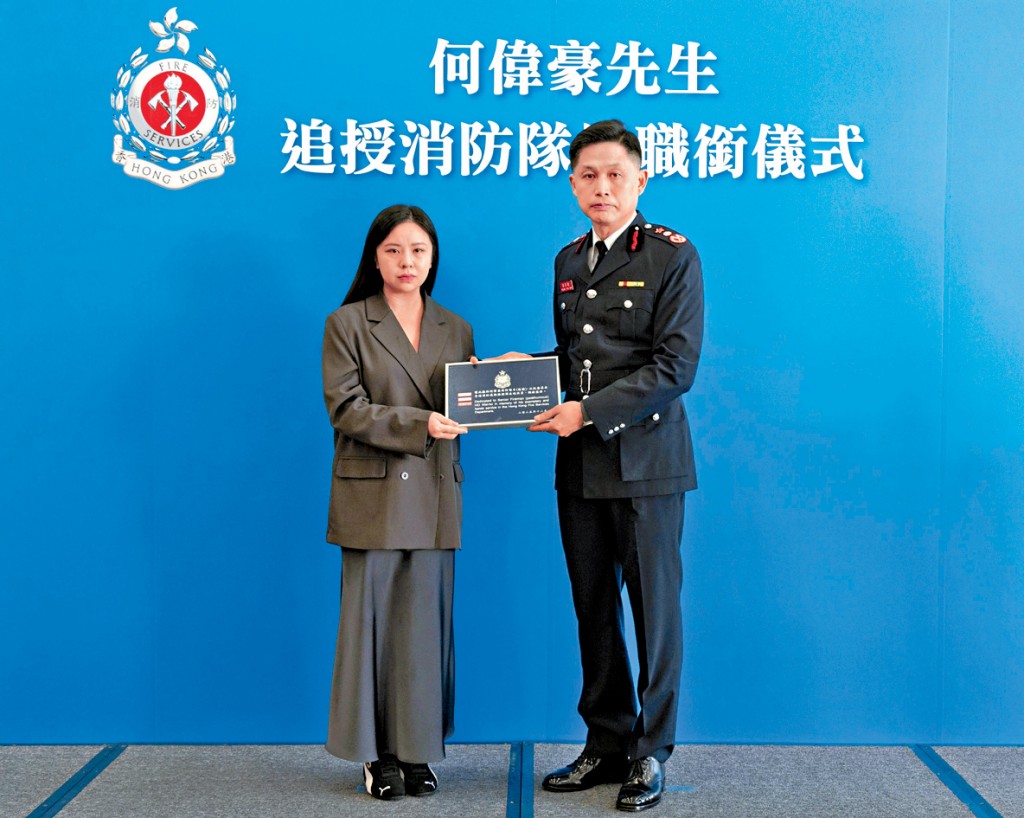 消防處處長楊恩健（右）頒授消防隊目階級章刺繡，由何偉豪的女友代表接受。