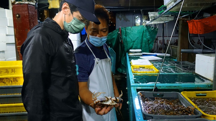 魚檔老闆教他如何捉蝦蟹不被致被弄傷。