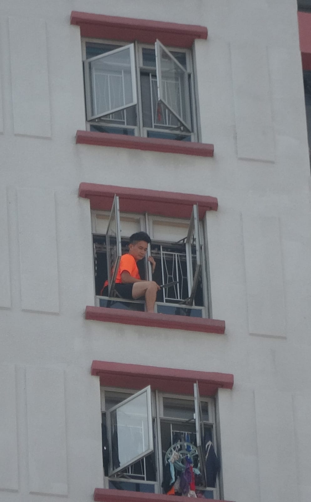 男子手持菜刀危坐高層單位外的窗邊。林思明攝