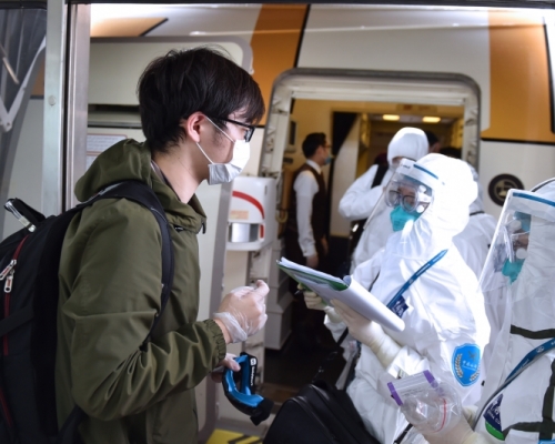 海關工作人員在飛機艙門處對入境人員相關情況進行詢問、記錄。(新華社)