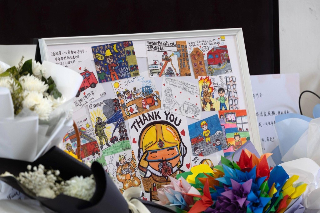 消防處助理處長（新界北）鄧榮華（右一）與何偉豪家屬觀看市民致送的鮮花和心意卡。