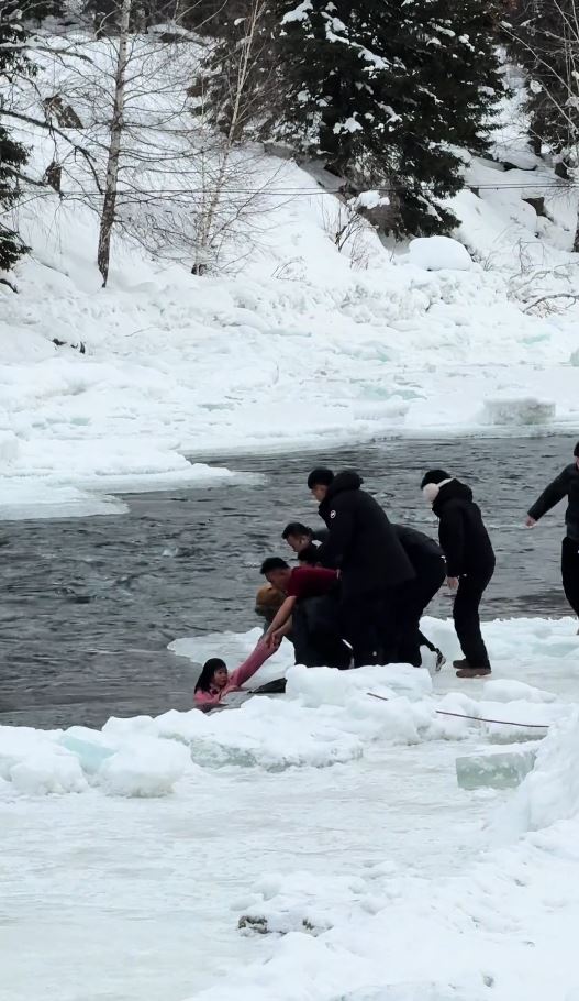女子越过警戒线拍照在冰面滑入河中被冲走，幸被民众合力救回。抖音＠小橙子