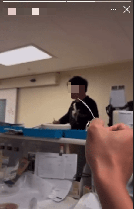 拍攝者以一支類以針筒的物品，向一名黑衣男子射水。網上影片截圖