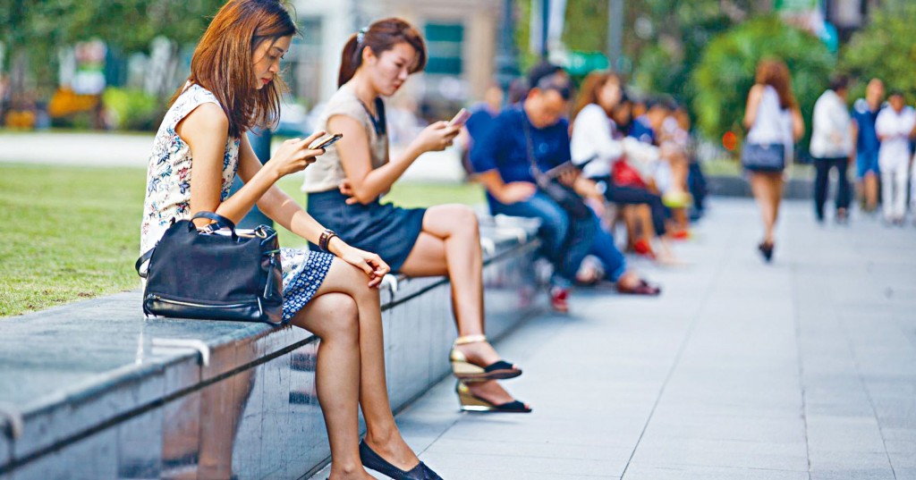 在新加坡莱佛士坊看手机的上班族。