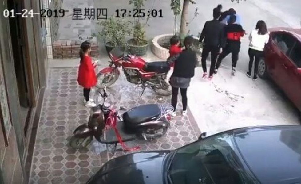 家屬包圍男子追打，女童就倒在母親懷抱中。網圖