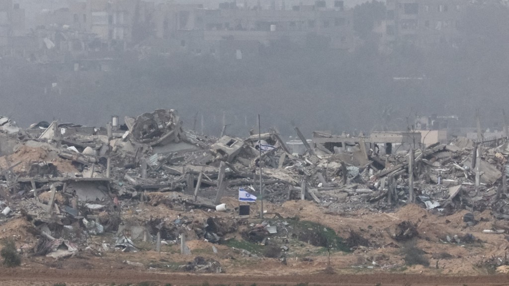 一面以色列国旗飘扬在加沙被摧毁建筑物的瓦砾堆中。路透社
