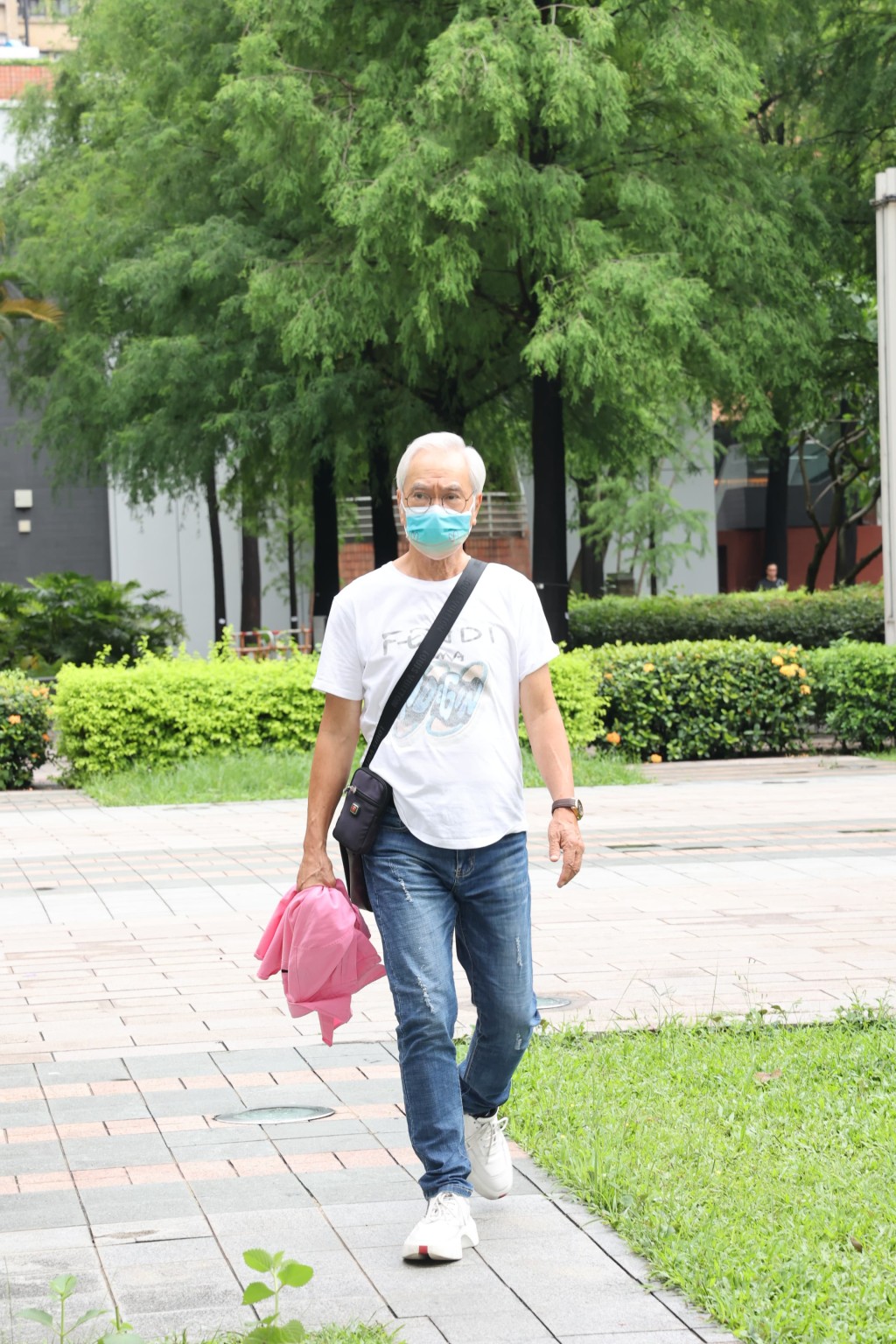 戴上口罩兼身穿「FENDI」白色T恤、拿著粉紅色衣服的李龍基到達法院。