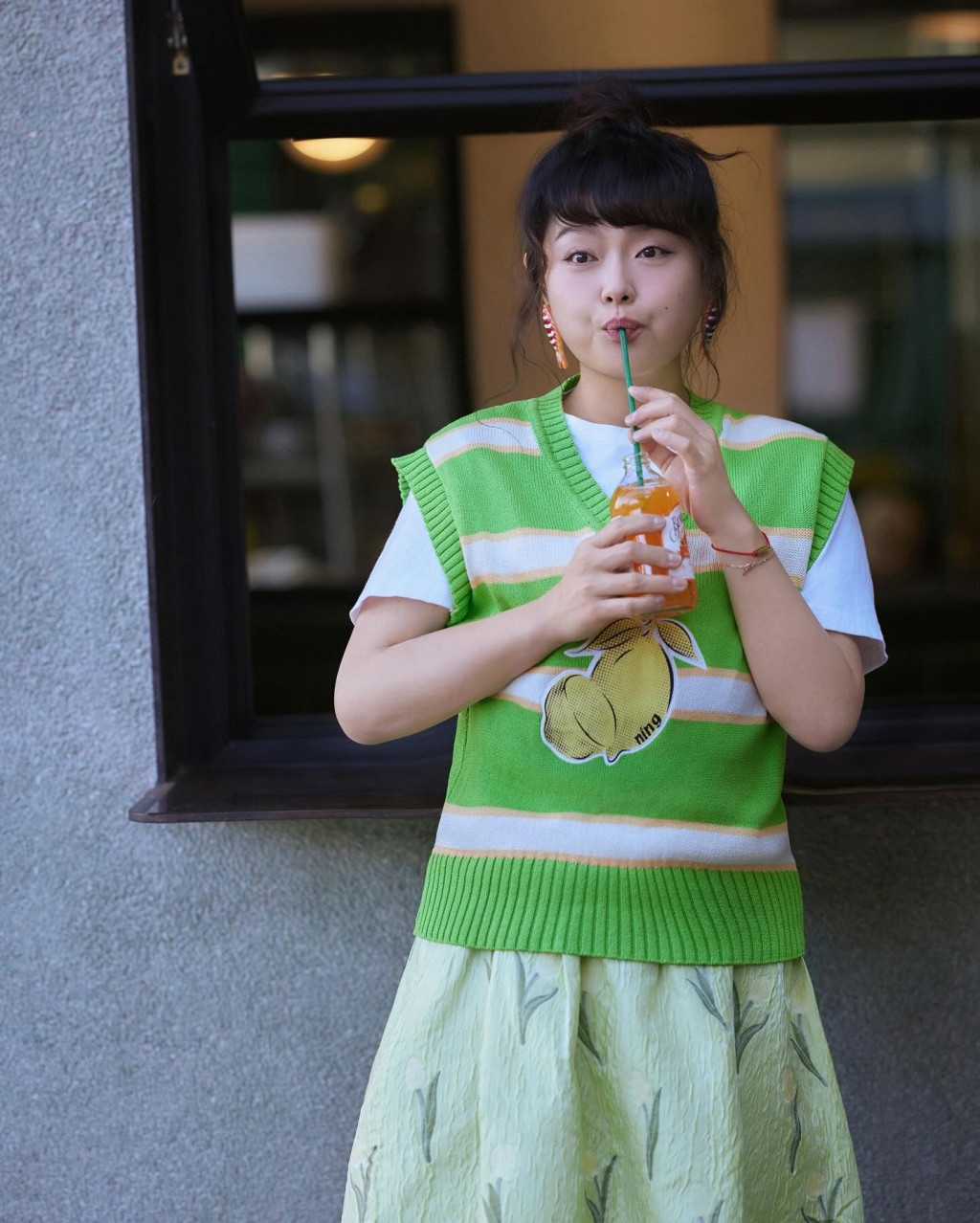 「细细粒」在月中端午节时分享几张身穿绿色飘逸长裙的照片，扎上丸子头食雪糕，少女味极浓。