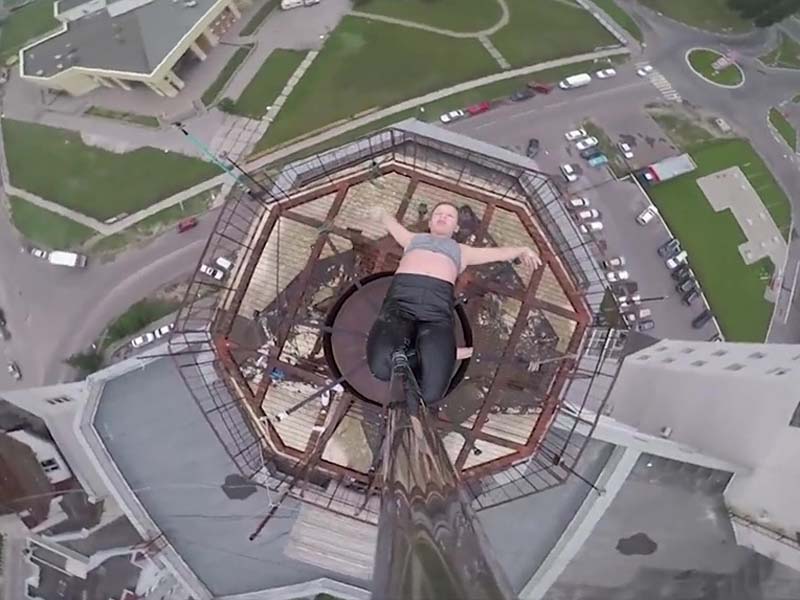 玛琳娜在楼顶的一根天线上跳起了钢管舞，同伴还用无人机拍下了她在空中的惊魂舞姿。(网图)