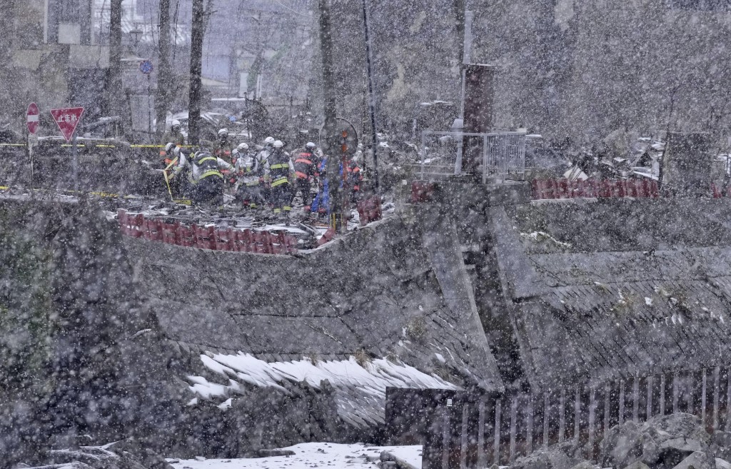 搜救人员冒雪搜寻失踪者。美联社